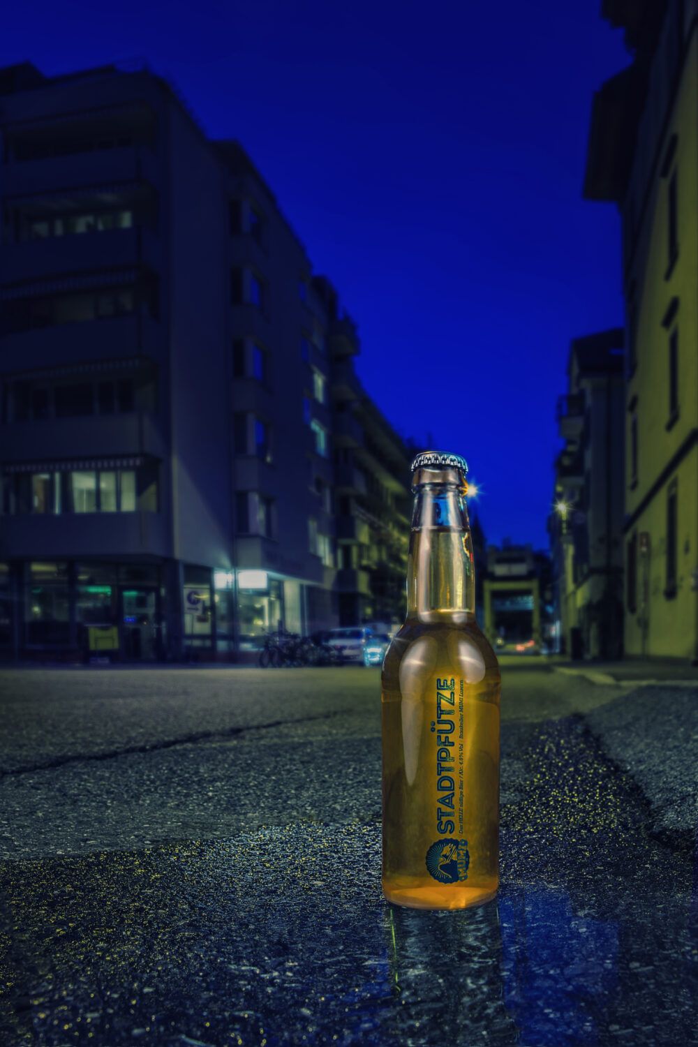 Eine Flasche Bier der Brauerei Stadtpfütze, fotografiert in einer Pfütze auf der Straße im Photostudio Luzern für Werbefotografie und Produktfotografie.